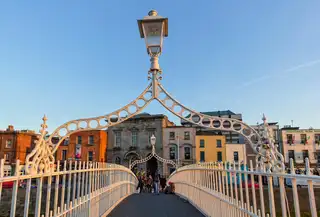The Ha'penny Bridge in Dublin in evening sun, looking along the deck under one of its iron lamp arches