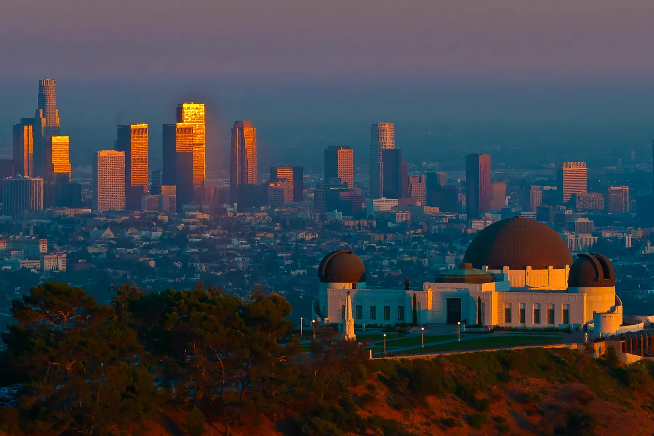 Griffith Observatory at sunset with the downtown Los Angeles towers behind it