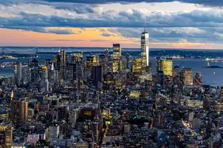Lower Manhattan from above at dusk, with One World Trade Center and the harbour behind