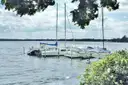 Segelboote vor Anker auf einem ruhigen See, eingerahmt von Bäumen