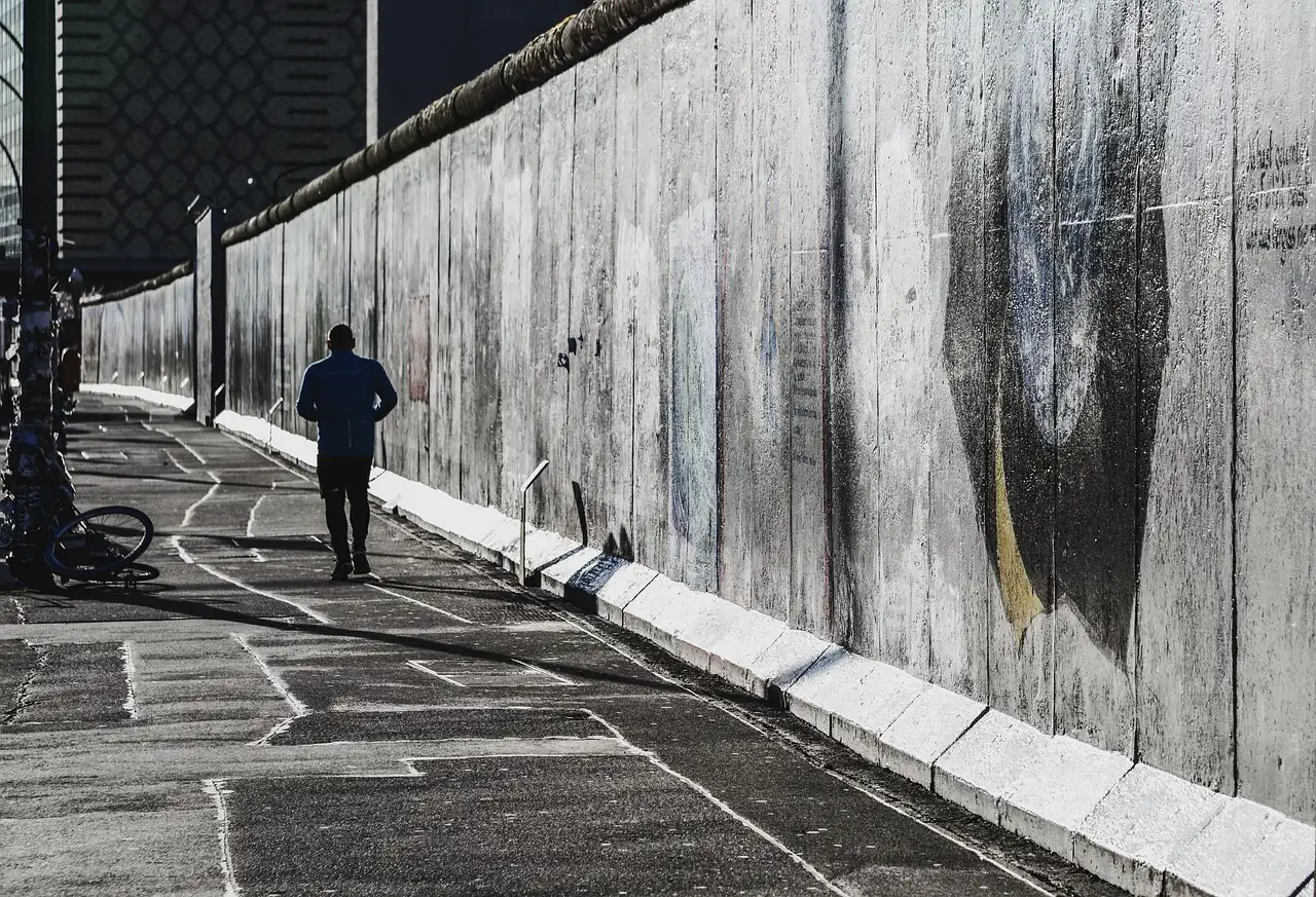 Ein langes erhaltenes Stück der Berliner Mauer neben einem Gehweg