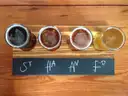 Vier Craft-Biere zum Probieren in kleinen Gläsern auf einem Holzbrett