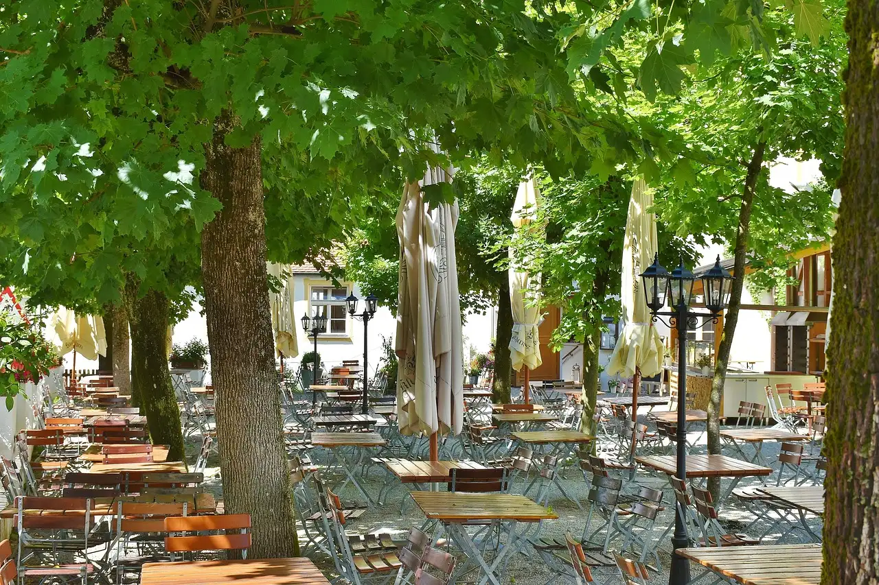 Tische und Stühle unter Bäumen in einem deutschen Biergarten