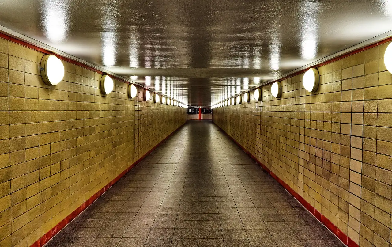 Ein leerer, gelb gekachelter U-Bahn-Tunnel mit runden Lampen in Berlin