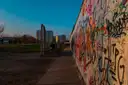 Ein Stück Berliner Mauer voller Graffiti neben einem Weg in der Abenddämmerung