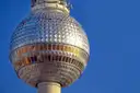 Die silberne Kugel des Berliner Fernsehturms vor blauem Himmel