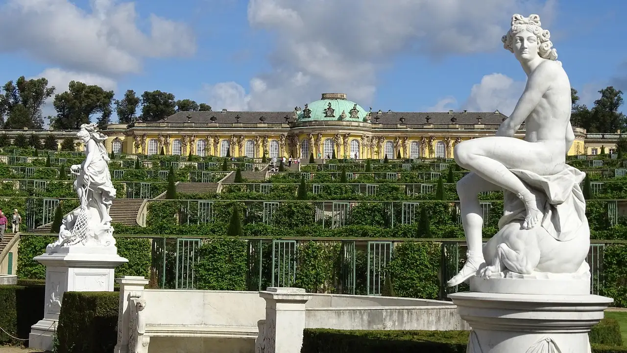 Eine weiße Marmorstatue vor den Terrassen und Schloss Sanssouci