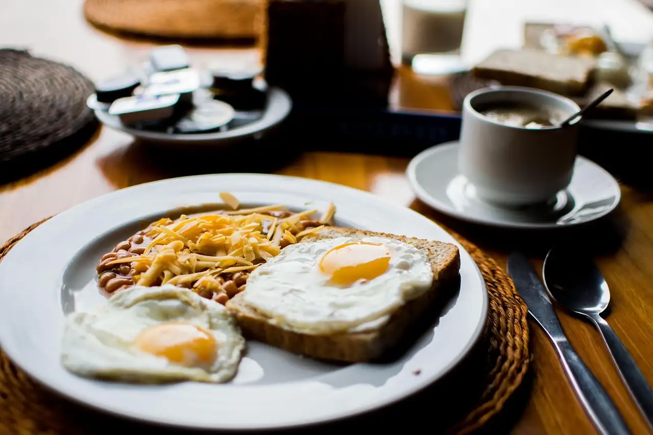 Ein Frühstücksteller mit Eiern und Toast neben einer Tasse Kaffee