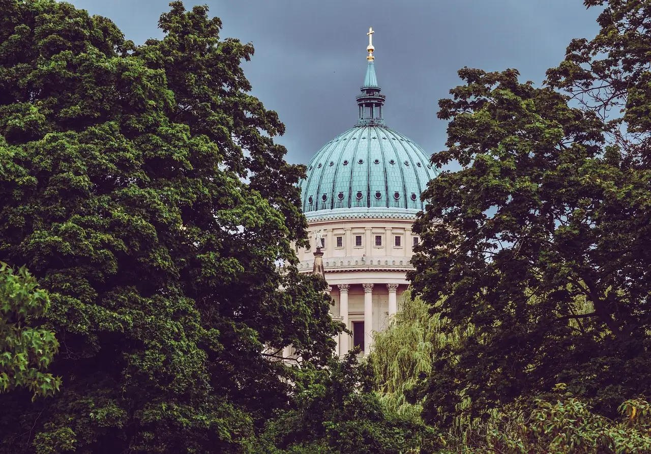 Die grüne Kuppel der Nikolaikirche in Potsdam hinter Bäumen