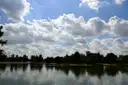Ein See im Hermann Park in Houston, am Ufer Bäume, darüber ein weiter blauer Himmel mit Wolken