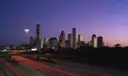 Die Türme von Downtown Houston in der Dämmerung über einer viel befahrenen Autobahn