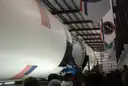 Eine liegende Saturn-V-Rakete in ihrer Halle im Space Center Houston, darüber Flaggen