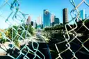 Die Türme von Downtown Houston an einem klaren Tag, durch einen Maschendrahtzaun neben einer Schnellstraße gesehen