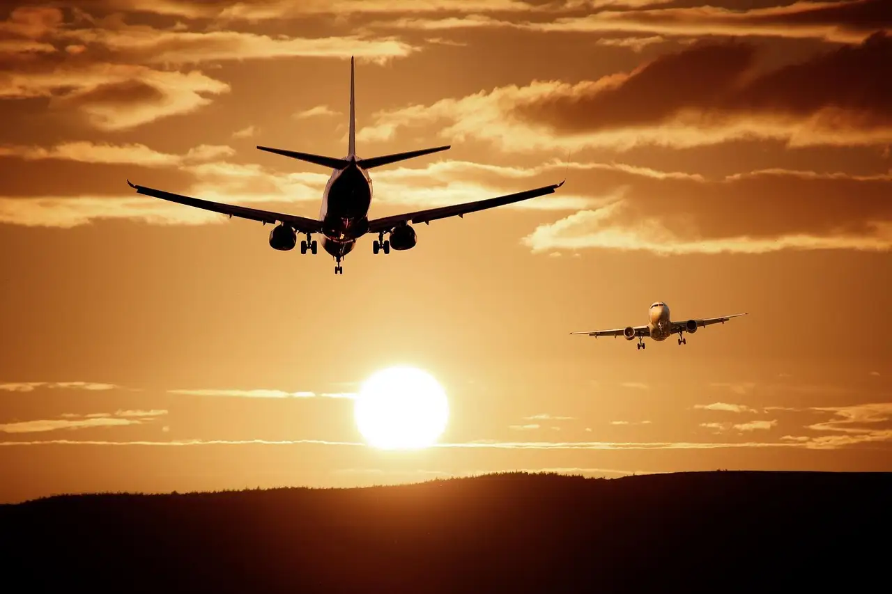 Zwei Passagierflugzeuge als Silhouette vor einem tief stehenden orangen Sonnenuntergang, ein allgemeines Flughafenfoto und kein Bild eines Flughafens in Houston