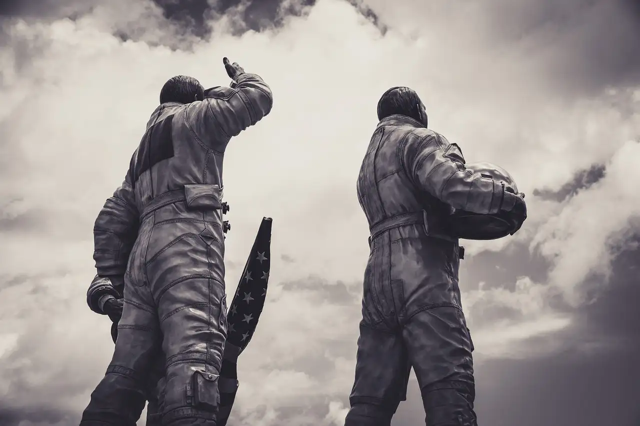 Zwei Bronzestatuen von Astronauten in Raumanzügen vor bewölktem Himmel
