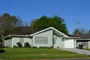 Ein eingeschossiges Haus mit grünem Rasen und Bäumen in einer Wohnstraße in Houston
