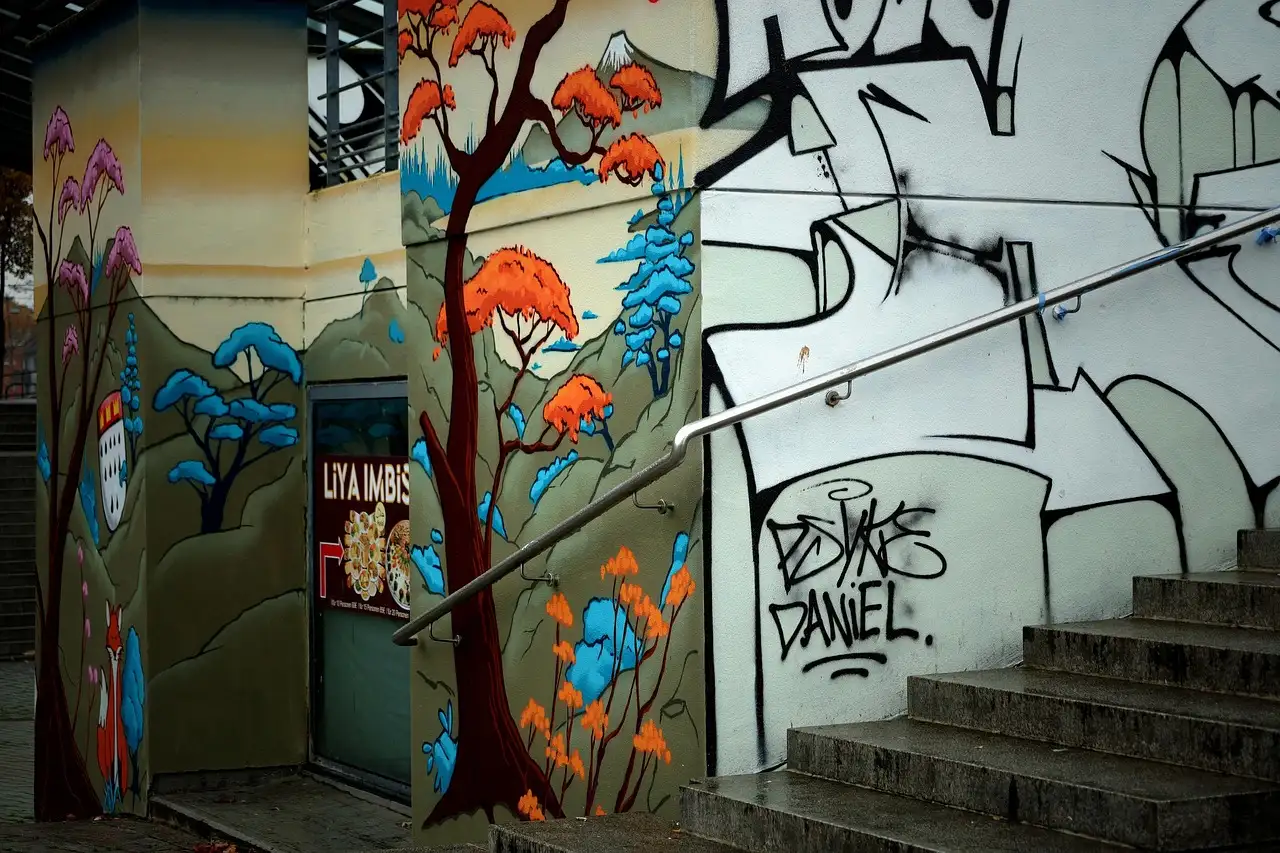 Gemalte Bäume und Graffiti an Mauern neben einer Betontreppe