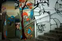 Gemalte Bäume und Graffiti an Mauern neben einer Betontreppe