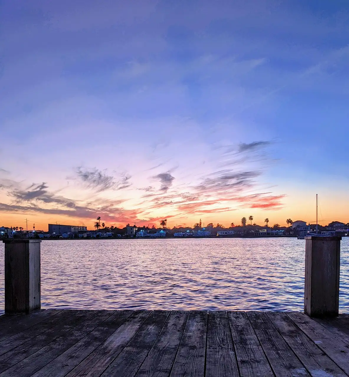 Ein Holzsteg am Wasser in Galveston unter einem bunten Abendhimmel