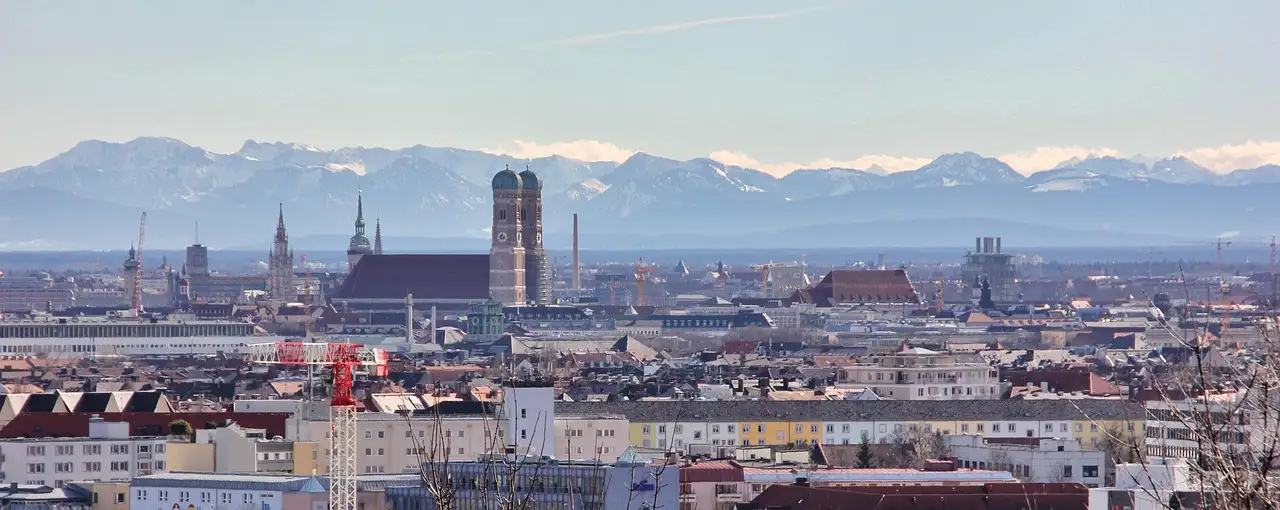 Münchner Skyline mit den zwei Türmen der Frauenkirche und den Alpen am Horizont