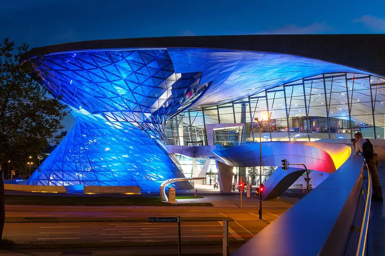 Der gläserne Doppelkegel der BMW Welt, in der Dämmerung blau beleuchtet