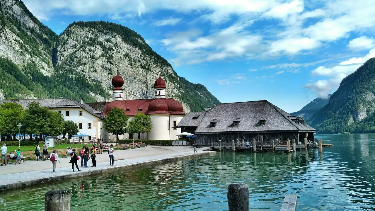Die Kirche St. Bartholomä mit roten Kuppeln am Königssee unter steilen Bergen