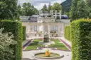 Schloss Linderhof hinter seinem Barockgarten und dem vergoldeten Brunnen