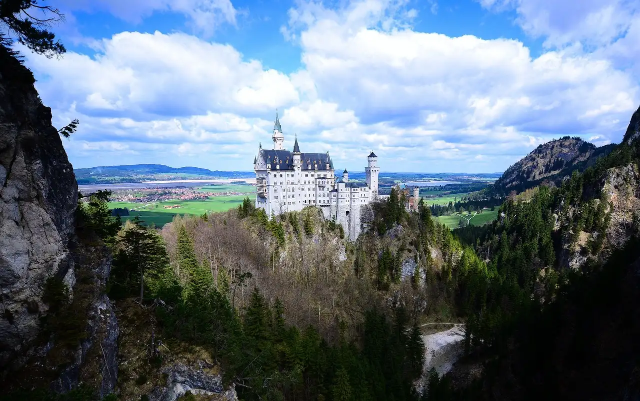 Schloss Neuschwanstein auf seinem bewaldeten Felsen, von der anderen Seite der Schlucht aus