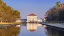 Schloss Nymphenburg am Ende seines langen Kanals mit Herbstbäumen im Abendlicht