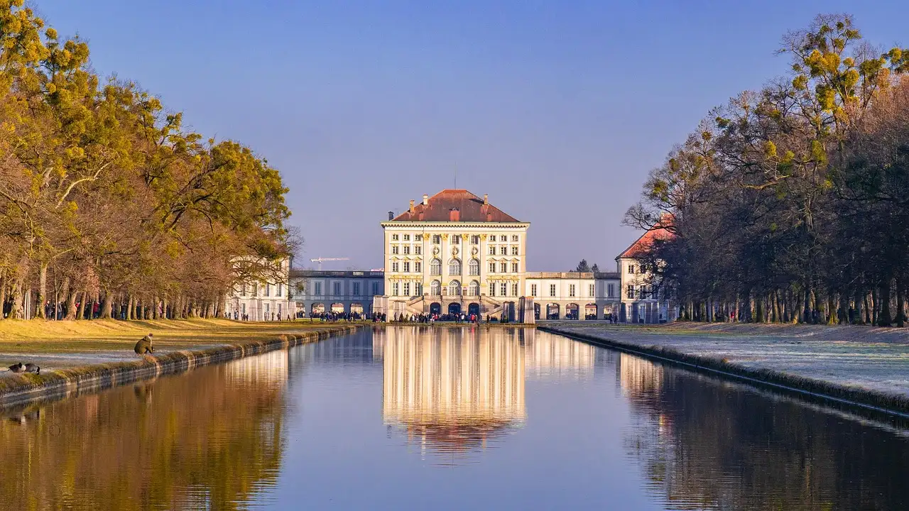 Schloss Nymphenburg am Ende seines langen Kanals mit Herbstbäumen im Abendlicht