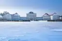 Schloss Nymphenburg im Winter, davor das gefrorene Wasser mit Schnee