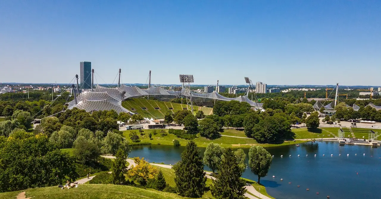 Das Zeltdach des Stadions und der See im Olympiapark München von oben, an einem klaren Tag