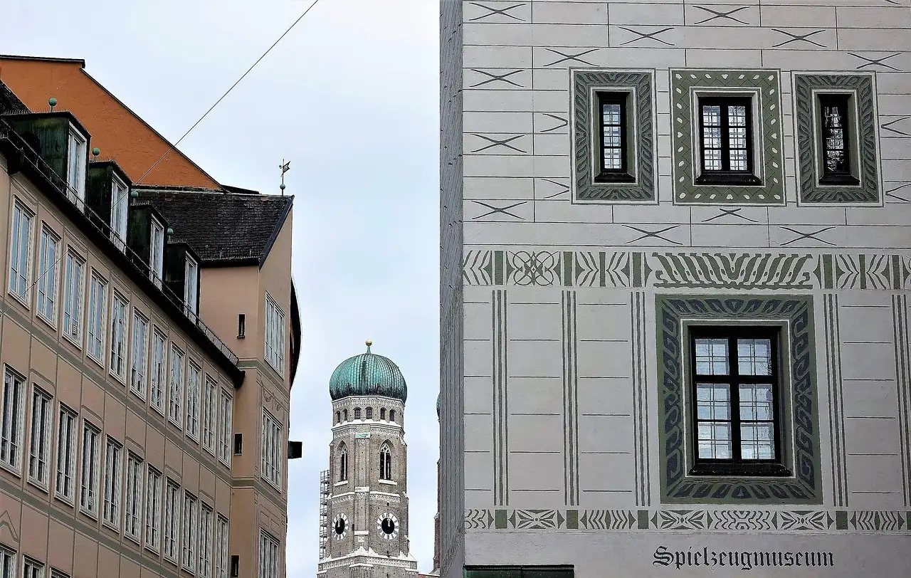 Ein Turm der Frauenkirche mit grüner Haube zwischen Altstadthäusern