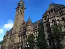 Uhrturm und Steinfassade der Old City Hall in Toronto unter blauem Himmel