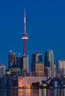 Der CN Tower nachts beleuchtet über den Türmen von Downtown und dem Hafen