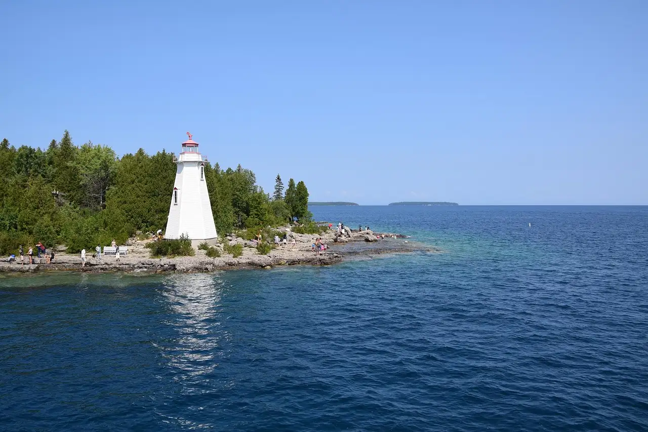 Ein kleiner weißer Leuchtturm auf einer felsigen Landspitze in Tobermory