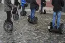 Segway-Fahrer auf einem Kopfsteinpflasterplatz, von der Hüfte abwärts gesehen