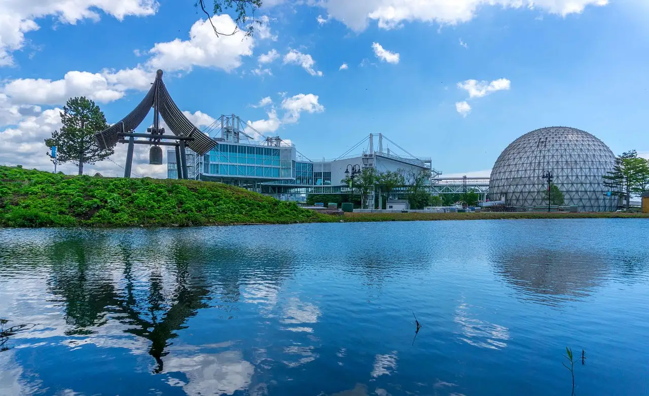 Die Kuppel der Cinesphere und die Pavillons von Ontario Place spiegeln sich in einer blauen Lagune unter hellem, bewölktem Himmel.