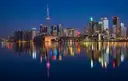 Torontos Skyline und der CN Tower nachts beleuchtet, gespiegelt im See