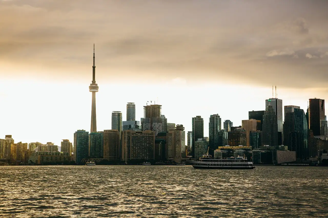 Ein Ausflugsboot im Hafen vor dem CN Tower und Downtown Toronto bei Sonnenuntergang