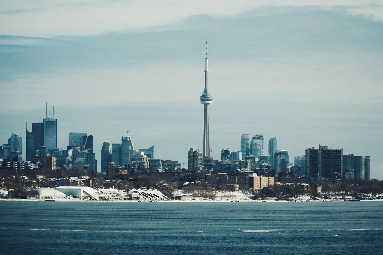 Der CN Tower und Downtown Toronto über den Ontariosee gesehen, an einem Wintertag mit Schnee am Ufer