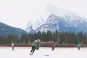 Menschen spielen Eishockey auf einem zugefrorenen See unter einem verschneiten Berg