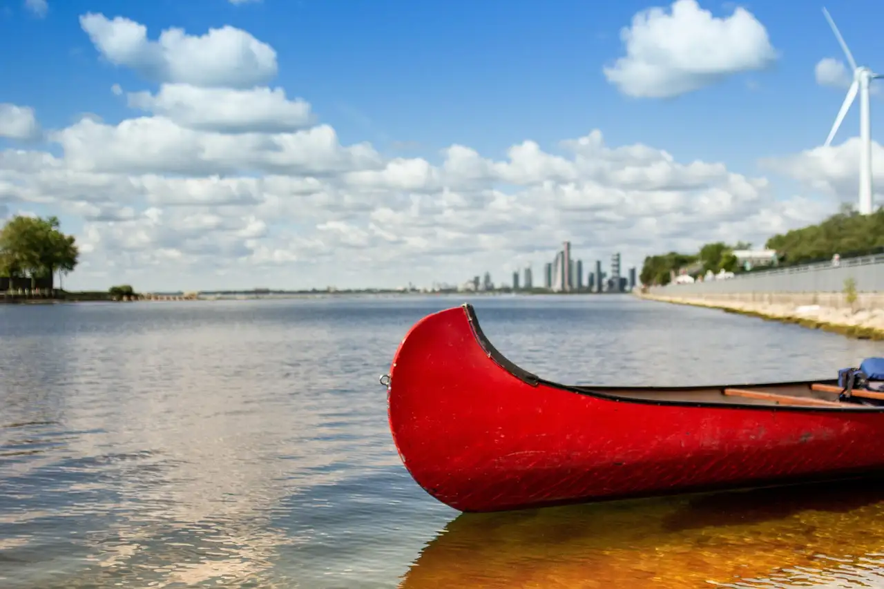Ein rotes Kanu auf ruhigem Wasser, weit über dem See eine Skyline