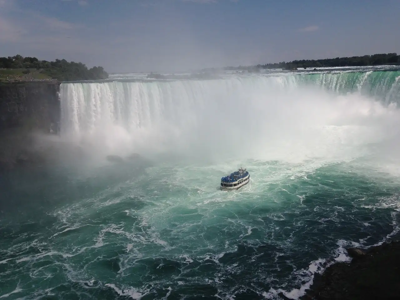 Die Horseshoe Falls in einer Gischtwolke, unten auf dem Fluss ein Ausflugsboot