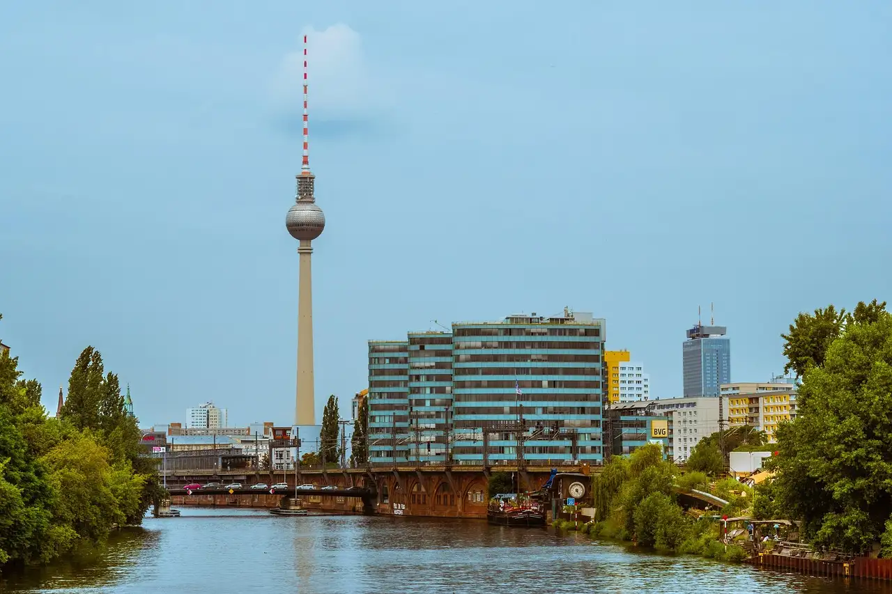 La Torre de Televisión de Berlín sobre edificios de oficinas y una orilla verde del Spree