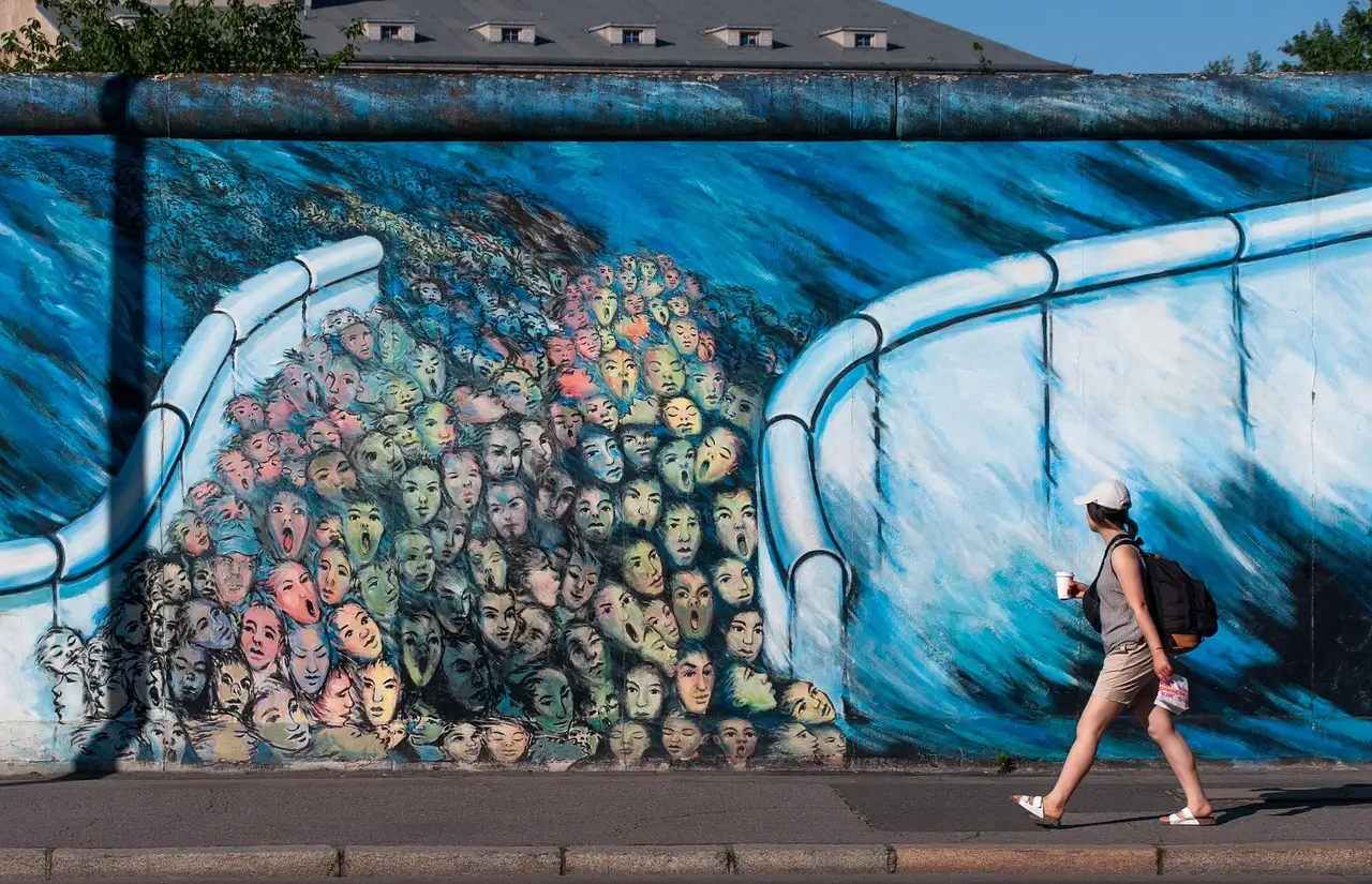 Una persona camina junto a un tramo pintado del Muro de Berlín en la East Side Gallery