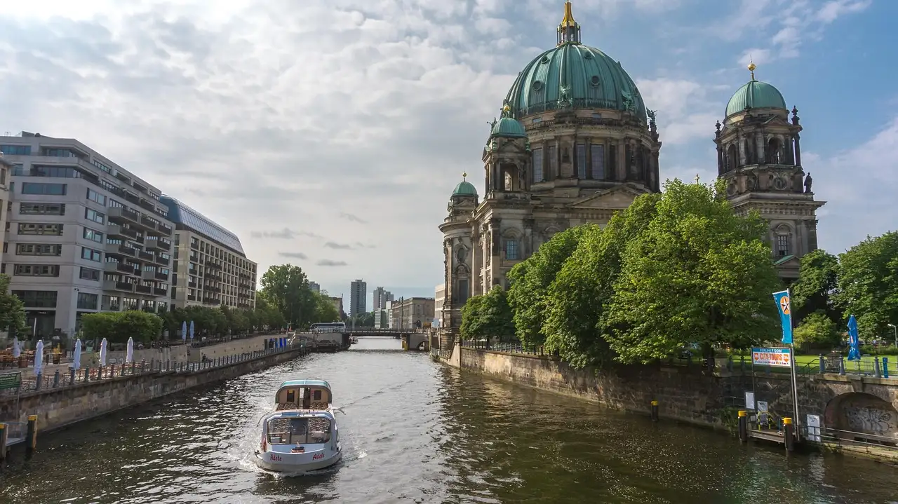 Un pequeño barco turístico por el Spree se aleja de las cúpulas verdes de la catedral de Berlín