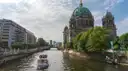 Un pequeño barco turístico por el Spree se aleja de las cúpulas verdes de la catedral de Berlín