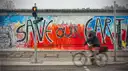 Un ciclista pasa junto a un tramo pintado del Muro de Berlín