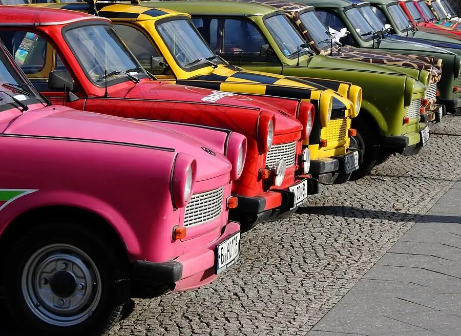 Una fila de Trabant de colores aparcados en una calle empedrada